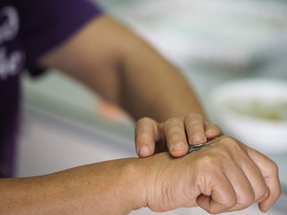 woman is standing with the finger to rub the gel alcoholic 70 percent mixture with gelatin on the back of the hand to prevent germs protect corona virus, covid19, hand Sanitizer