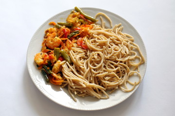 Spaghetti with fried vegetables and shrimp. Italian food. Eastern cuisine.