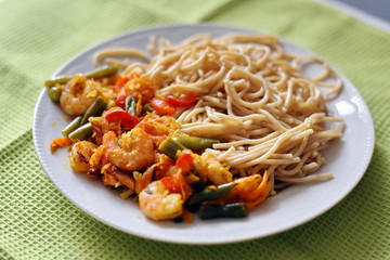 Spaghetti with fried vegetables and shrimp. Italian food. Eastern cuisine.