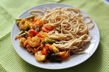 Spaghetti with fried vegetables and shrimp. Italian food. Eastern cuisine.