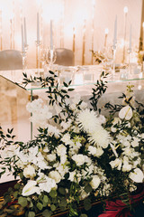 Wedding banquet. The festive table is decorated with flower arrangements and decorative lamps; there are candles, plates and glasses on the table.