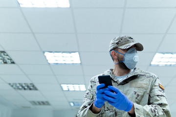 coronavirus. uniformed military man with his mobile phone and laptop.