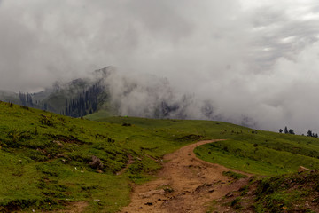 Muddy road in the mountains with clouds