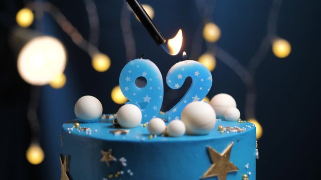 Birthday cake number 92 stars sky and moon concept, blue candle is fire by lighter and then blows out. Copy space on right side of screen if required. Close-up and slow motion