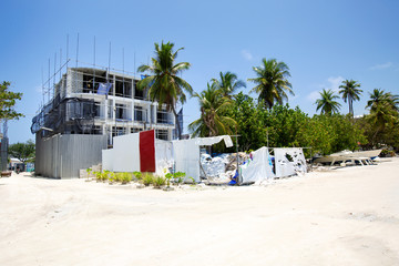 Unfinished building at tropical street with coconut palm trees