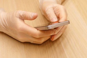 a hands in a protective disposable gloves holding a grey mobile phone