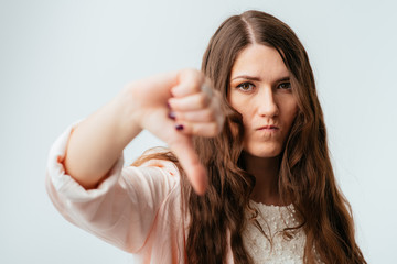 Obraz premium long-haired beautiful brunette girl showing thumb down isolated on white background