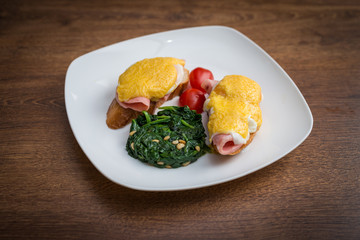 Traditional omelet with vegetables, spinach, tomatoes and herbs on a wooden table. Classic european breakfast.