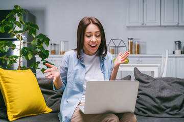 Young woman celebrating money win after making bets online at bookmakers website using her laptop