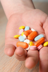 Several colored tablets in hand close-up. Concept of assistance in case of illness. Help with viral infection.