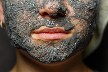 Beautiful young girl with a tonic foam mask on her face and a towel tied with hair