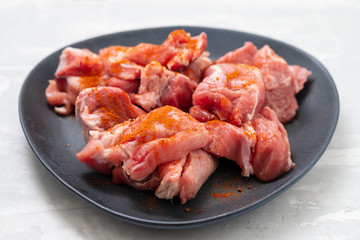 marinated meat on black dish on ceramic background