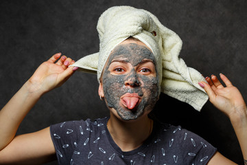 Beautiful young girl with a tonic foam mask on her face and a towel tied with hair