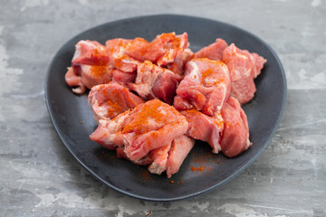 marinated meat on black dish on ceramic background