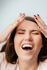 long-haired beautiful young brunette woman screaming and holding his head