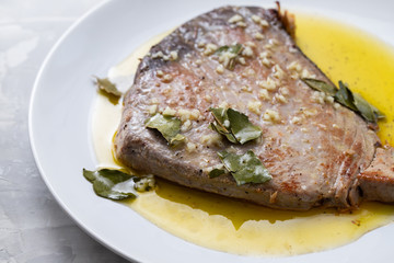 fried tuna with garlic, bay leaf and olive oil on white plate