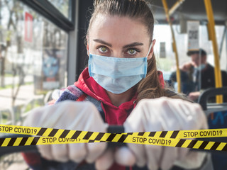 COVID-19 Public transport bus during the coronavirus pandemic. Young woman in protective medical...