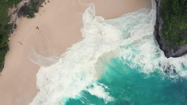 Aerial shot of waves crashing in over a beach on Nusa Penida in Indonesia
