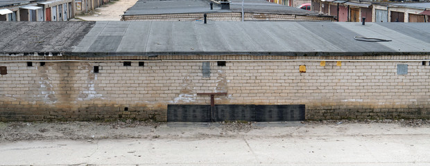 Ruberoid roofs  and white bricks walls of a large garage cooperative in the residential area