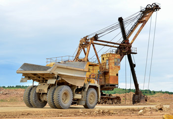 Obraz premium Big mining truck transport of minerals in the quarry. Open-cast mining of extracting rock or minerals from the earth. Largest dolomite deposit open-pit mining Gralevo, Belarus, Vitebsk region