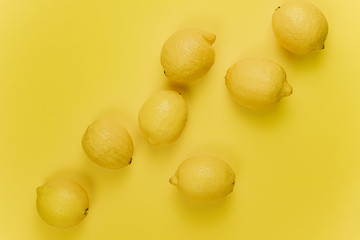 Ripe juicy lemons, green leaves on bright yellow background. Lemon fruit, citrus minimal concept, vitamin C. Creative summer minimalistic background. Flat lay, top view, copy space