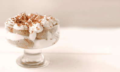 Tiramisu cake in glass, classic Italian dessert made of cookies savoiardi, mascarpone cream and cocoa. Coffee and diary dessert, homemade. selective focus. copy space for text. 