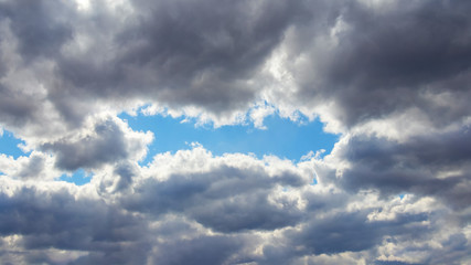 Obraz premium The sky is covered with gray clouds, through which you can see a piece of blue sky