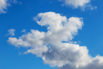 White clouds of unusual shape in the blue sky on a beautiful day