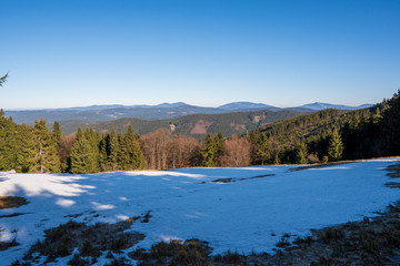 Meadows at the end of winter with snow and mountains in the background, beskydy czech