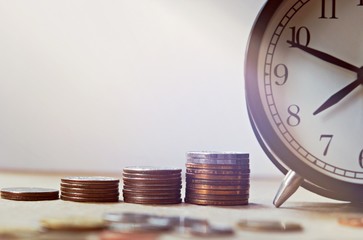 Vintage alarm clock and group of growing coins placed on the floor, selective focus and shallow depth of field, investment concept. growing on coin, Business Finance and Save Money.