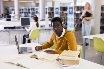 Confident african-american man working on laptop in public library