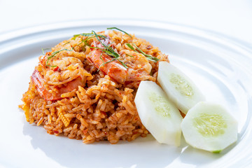 Spicy Thai food or Asia food closeup side view Shrimp Red Curry Fried Rice seafood, Garnish with shredded kaffir lime leaves and sliced cucumber on a clean round white dish for cooking delicious meals