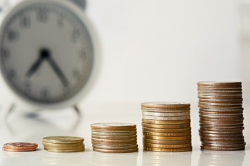 group of growing coins placed on the floor with blurred vintage alarm clock, selective focus and shallow depth of field, investment concept. growing on coin, Business Finance and Save Money.