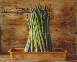 bunch of asparagus on wooden background and clay pot