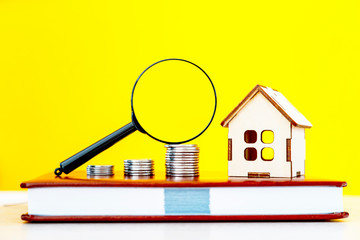 toy house, coins and magnifying glass on a real estate agent's notebook, selective focus, tinted image