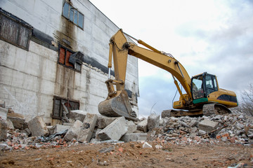 Yellow excavator with bucket at demolition of tall building. Hydraulic machine for demolish....