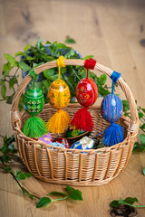 Colorful hand painted Easter eggs, made of wood in a brown wicker basket – decoration of a holiday table during celebration