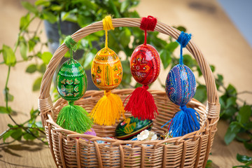 Beautiful, colorful hand painted Easter eggs, made of wood in a brown wicker basket – decoration of a holiday table during celebration