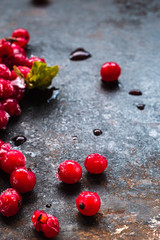 scattered frozen red currants closeup lie on a rusty surface. copy space. vertical.