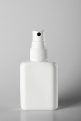 Instant antiseptic hand sanitizer mist spray with antibacterial alcohol liquid. White plastic bottle with atomizer pump on gray background, no label. COVID-19, Coronavirus prevention, hygiene measure.