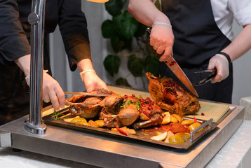 duck baked in  juice with lingonberry sauce on a tray, cook's hands, cooked duck