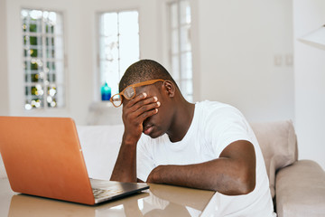 man of African appearance at home in front of a laptop