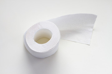 Roll of white toilet paper on a light gray background