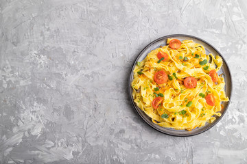 Reginelle semolina pasta with tomato, eggs and microgreen sprouts on a gray concrete background. Top view, copy space.