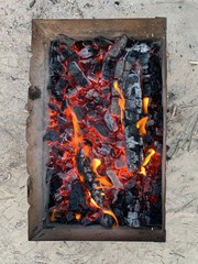 Hot grill during a picnic in the yard. Metallic roaster with coal, in nature. Fire in a folding grill for cooking.