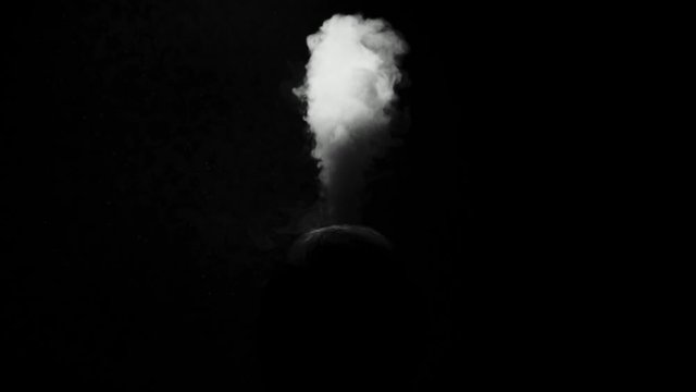 the silhouette of a man on a dark background exhales clouds of smoke