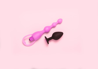 Adult sex toys and accessories on pink background.