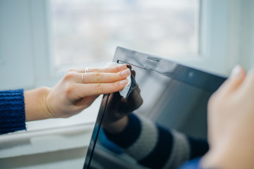 people, housework, electronics and housekeeping concept - close up of woman hand cleaning laptop computer screen with cloth