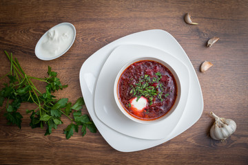 Red borscht soup with dill in white bowl.