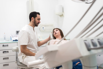 Fototapeta premium Portrait of a bearded dentist male explaining procedure to a female patient